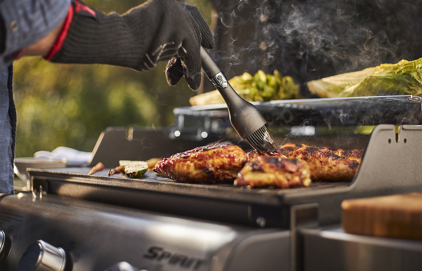 Grillmeister bestreicht Fleisch auf dem Gasgrill mit Marinade