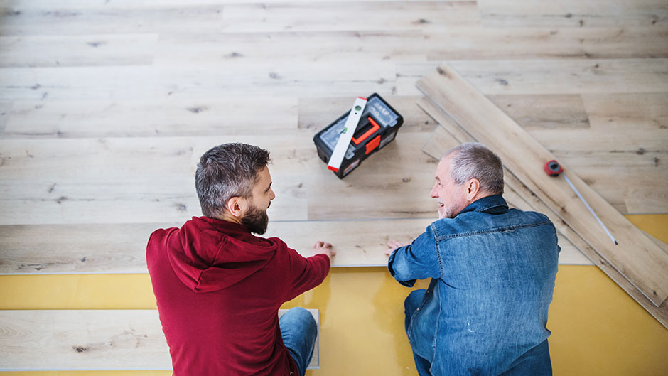 Zwei Männer verlegen Klick Vinyl Boden auf gelbem Untergrund