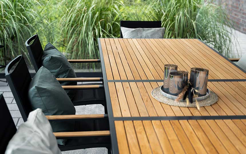Gartentisch aus Holz mit schwarzen Stühlen und Deko