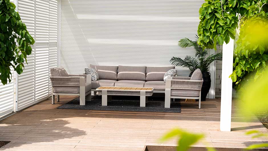 Holzterrasse mit weißem Sichtschutz und Loungemöbeln im Garten