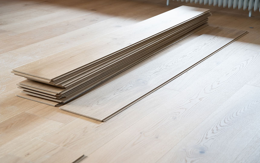 Gestapelte helle Vinyl-Designboden-Dielen auf hellem Holzboden in einem Raum mit Tageslicht